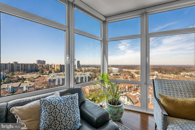 sunroom / solarium featuring a wall of windows, a city view, and wood finished floors