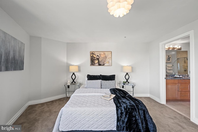 carpeted bedroom with baseboards, a notable chandelier, and ensuite bath