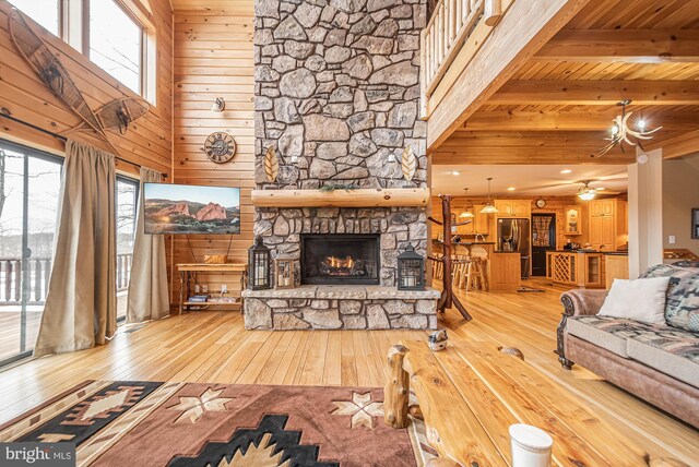 living room with light wood-type flooring, a healthy amount of sunlight, a fireplace, and beamed ceiling