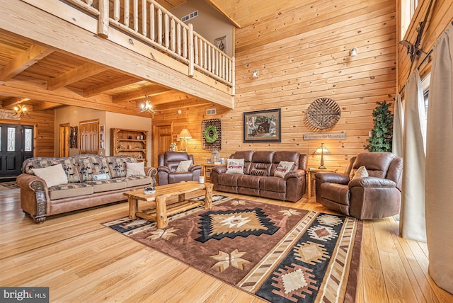 living area featuring plenty of natural light, wood walls, a high ceiling, and hardwood / wood-style flooring