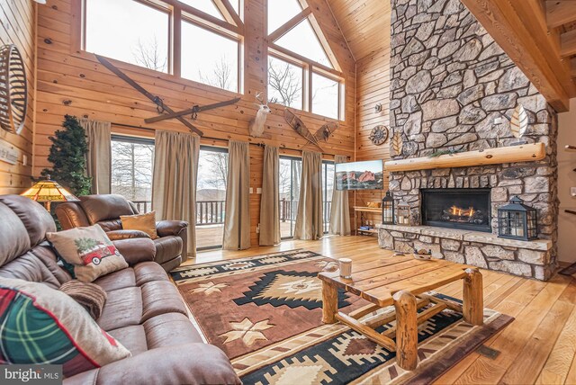 living area with a fireplace, wooden walls, high vaulted ceiling, wood ceiling, and hardwood / wood-style flooring