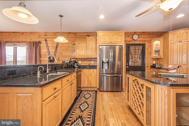kitchen featuring wooden walls, stainless steel refrigerator with ice dispenser, a sink, and light wood-style floors