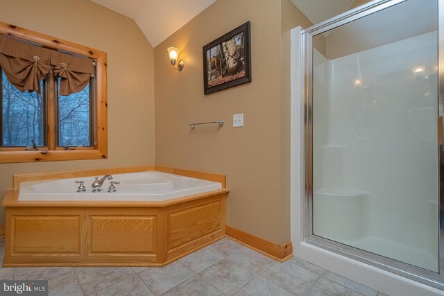 bathroom featuring baseboards, vaulted ceiling, a garden tub, and a stall shower