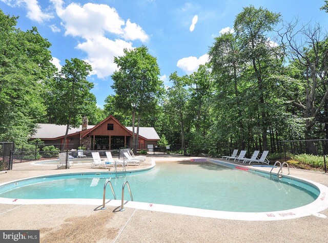 community pool with fence and a patio area