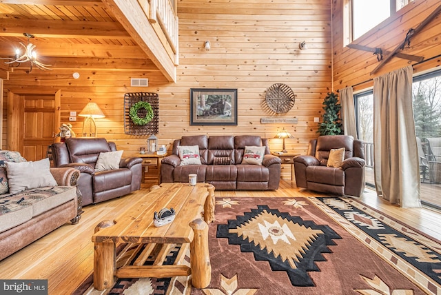 living room with beam ceiling, wooden walls, wood ceiling, hardwood / wood-style flooring, and a notable chandelier