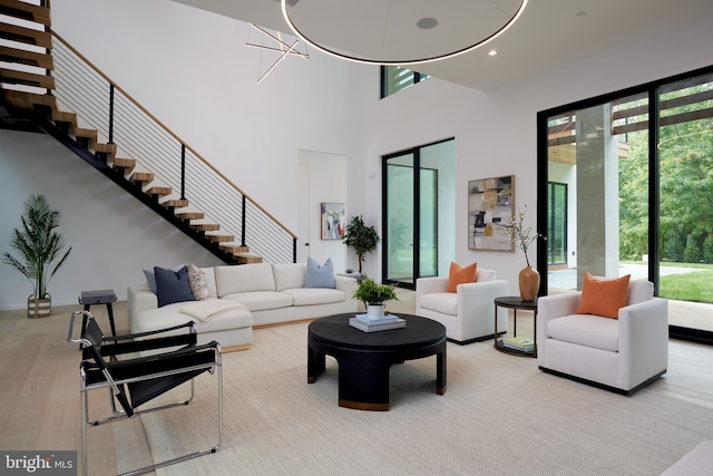 living room with a towering ceiling, stairs, wood finished floors, a chandelier, and recessed lighting