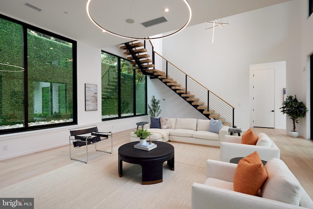 living area with a towering ceiling, stairs, wood finished floors, and visible vents
