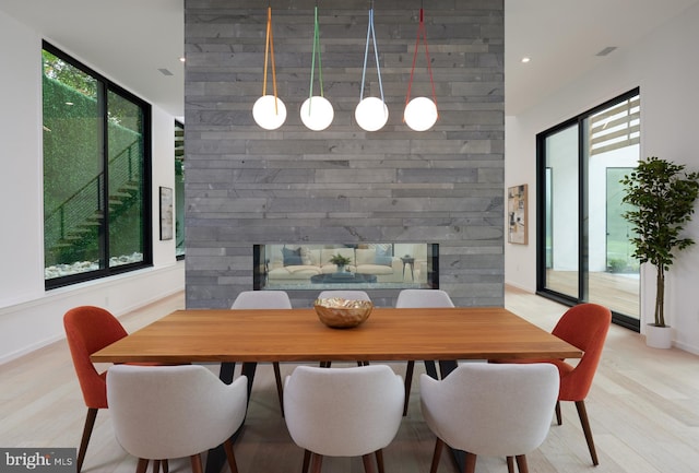 dining space featuring baseboards, recessed lighting, a multi sided fireplace, and light wood finished floors