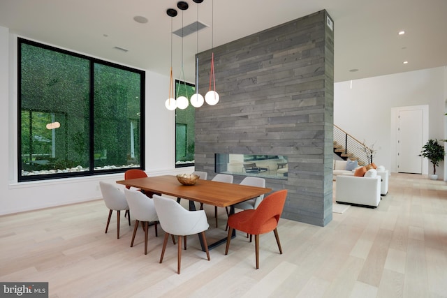 dining area with stairway, a stone fireplace, wood finished floors, and visible vents