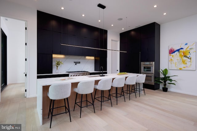 kitchen with dark cabinetry, a sink, light wood finished floors, and modern cabinets