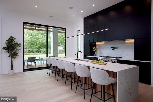 kitchen with a sink, decorative backsplash, modern cabinets, and a breakfast bar area