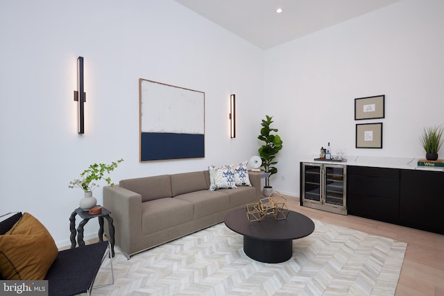 living room with wine cooler, baseboards, a bar, and light wood-style flooring
