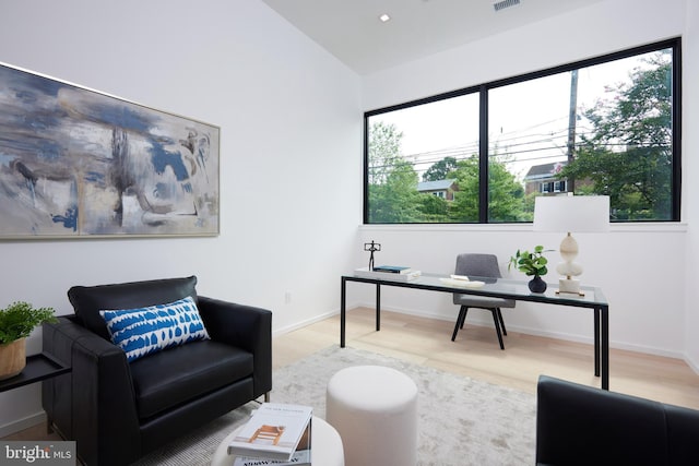 office area featuring baseboards, visible vents, wood finished floors, and lofted ceiling