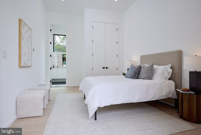 bedroom with baseboards, a closet, and light wood-style flooring