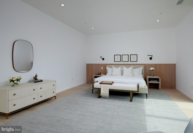 bedroom with a wainscoted wall, light wood-style flooring, and visible vents