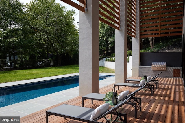 outdoor pool with fence, a yard, a deck, and area for grilling