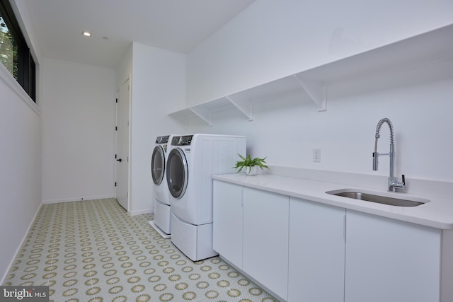 clothes washing area featuring washer and dryer, cabinet space, a sink, baseboards, and light floors