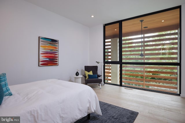 bedroom featuring a wall of windows and wood finished floors