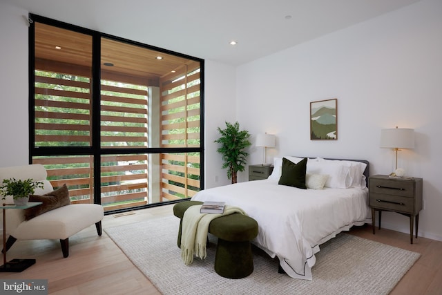 bedroom featuring recessed lighting, expansive windows, and wood finished floors