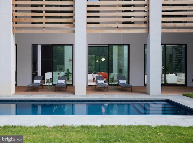 back of property with stucco siding, an outdoor pool, and a balcony