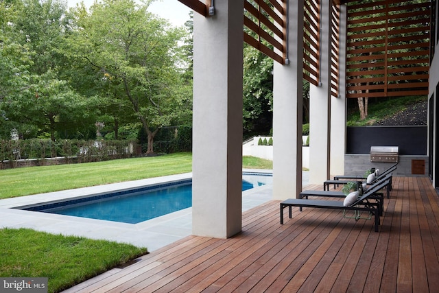 outdoor pool with a lawn, a fenced backyard, area for grilling, and an outdoor kitchen