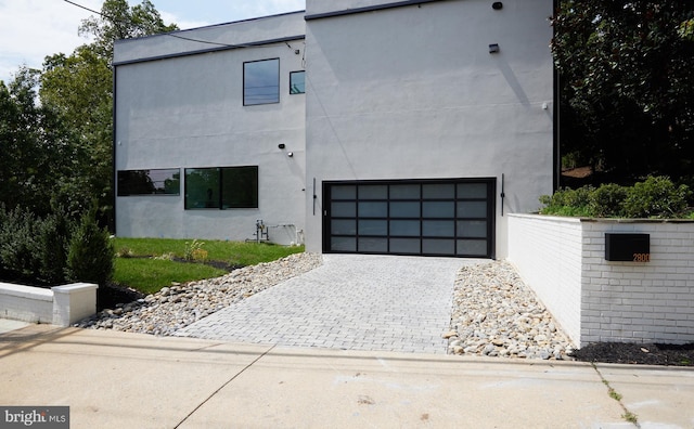 view of side of home with decorative driveway, a garage, and stucco siding