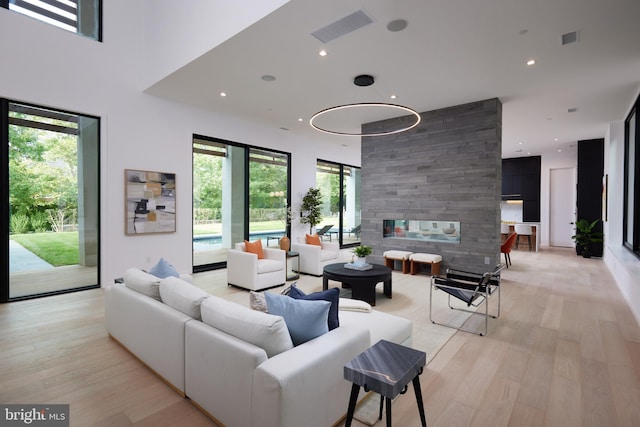 living room with visible vents, light wood-style floors, and a stone fireplace