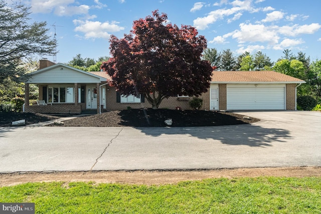 view of front of house featuring an attached garage, brick siding, driveway, and a chimney