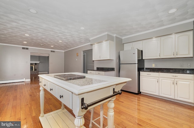 kitchen with a baseboard heating unit, freestanding refrigerator, light wood-type flooring, recessed lighting, and white cabinetry
