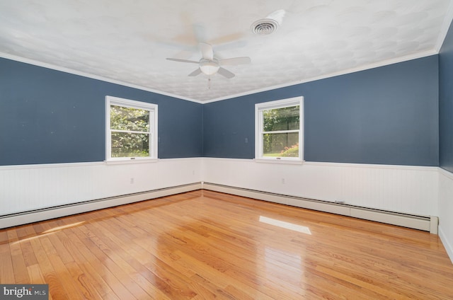 spare room with wainscoting, visible vents, plenty of natural light, and hardwood / wood-style flooring
