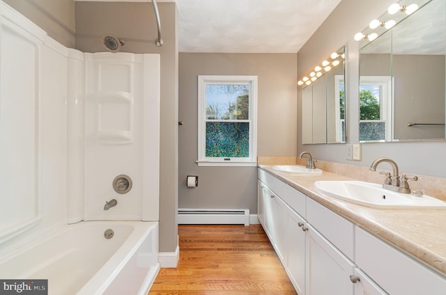 full bath featuring a sink, bathing tub / shower combination, wood finished floors, and a baseboard heating unit