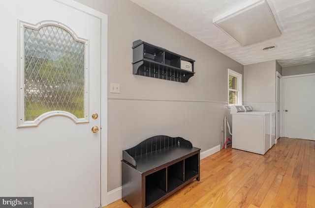 laundry room featuring light wood-style flooring, laundry area, a wainscoted wall, washer and clothes dryer, and visible vents