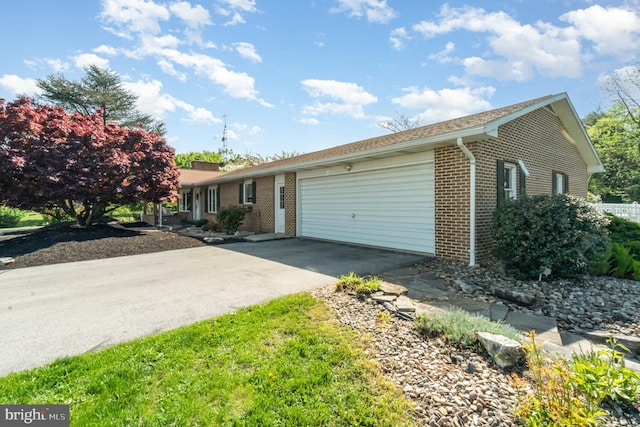 ranch-style house featuring an attached garage, concrete driveway, and brick siding