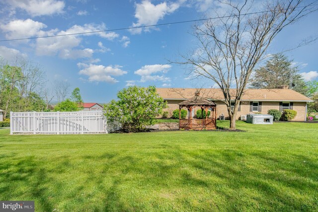 view of yard featuring a hot tub, a gazebo, and fence