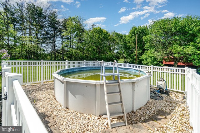 view of swimming pool featuring a lawn, a fenced in pool, and fence