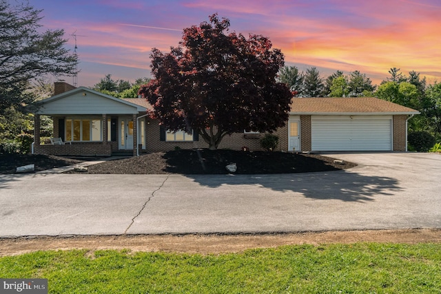 view of front of house featuring concrete driveway, brick siding, and covered porch
