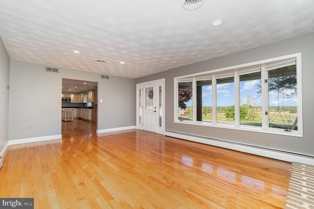 unfurnished living room with light wood-type flooring, recessed lighting, baseboard heating, and visible vents