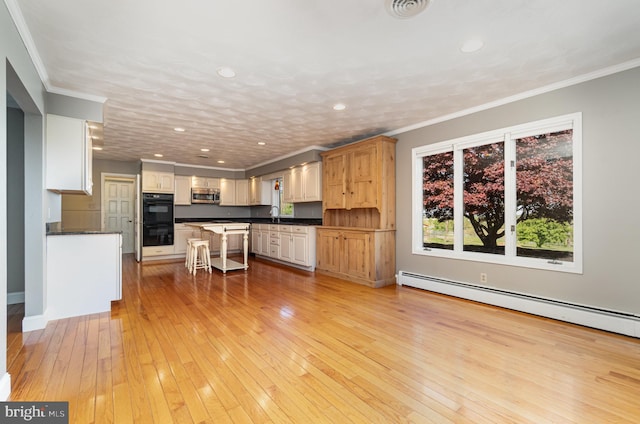 kitchen featuring a sink, dark countertops, dobule oven black, stainless steel microwave, and a baseboard radiator