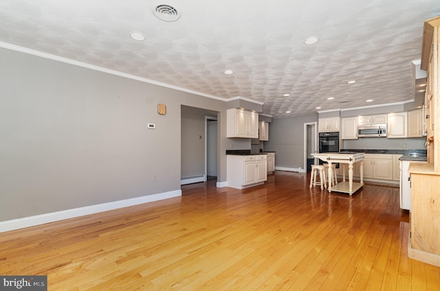 unfurnished living room with a baseboard heating unit, baseboards, light wood finished floors, and recessed lighting
