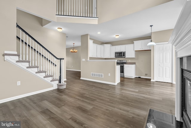9 Ryan Ct, Telford, PA 18969 - unfurnished living room with visible vents, stairway, dark wood-style flooring, baseboards, and a glass covered fireplace