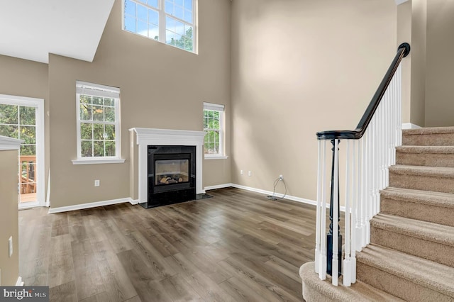 9 Ryan Ct, Telford, PA 18969 - unfurnished living room featuring wood finished floors, a towering ceiling, stairway, baseboards, and a fireplace with flush hearth