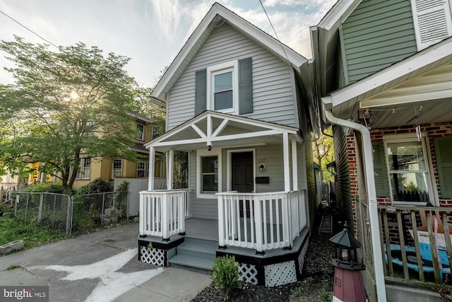 shotgun-style home with fence and covered porch
