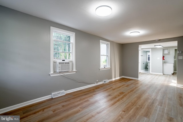 empty room with baseboards, visible vents, a wealth of natural light, and light wood finished floors