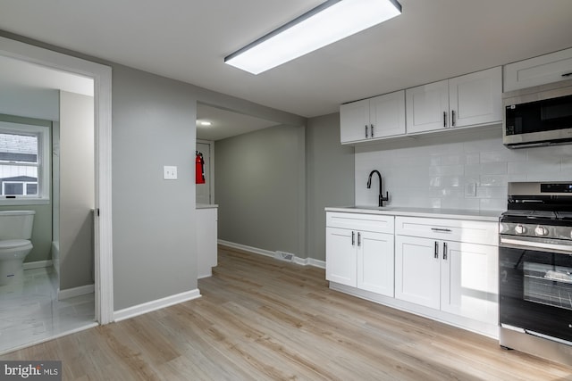 kitchen with baseboards, light countertops, tasteful backsplash, a sink, and appliances with stainless steel finishes