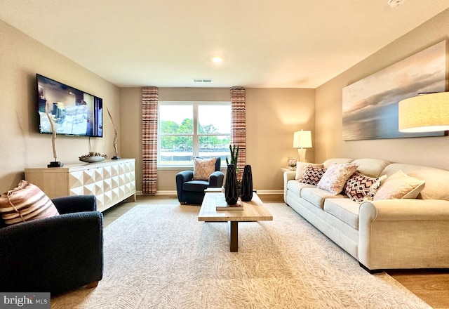 living area with baseboards, visible vents, and wood finished floors