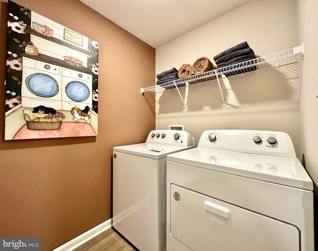 clothes washing area with baseboards, laundry area, wood finished floors, and washer and clothes dryer