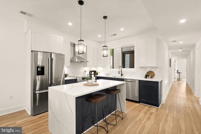 1251 Morse St NE Unit Ph3, Washington, DC 20002 - kitchen featuring decorative backsplash, wall chimney exhaust hood, white cabinetry, a sink, and appliances with stainless steel finishes
