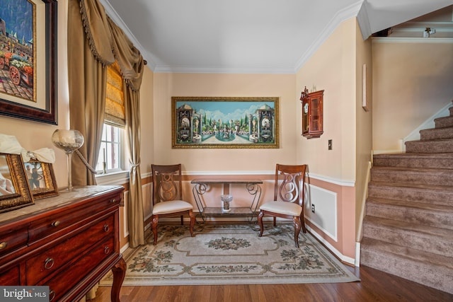 sitting room with wainscoting, ornamental molding, wood finished floors, and stairway