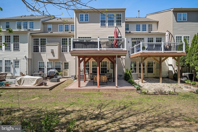 rear view of house with central air condition unit, a wooden deck, a yard, and a patio area