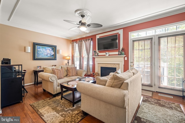 living area featuring crown molding, ceiling fan, a healthy amount of sunlight, and a fireplace